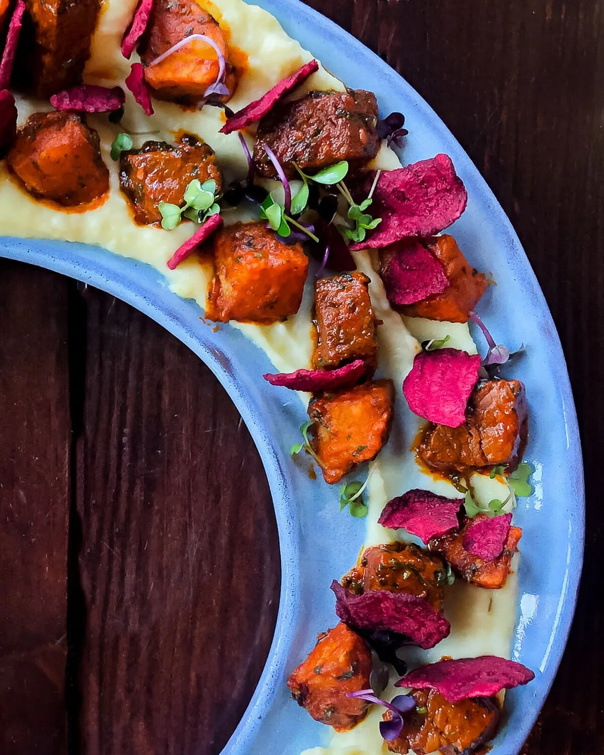 Shepherd's pie portions with colorful garnishes on a blue platter.