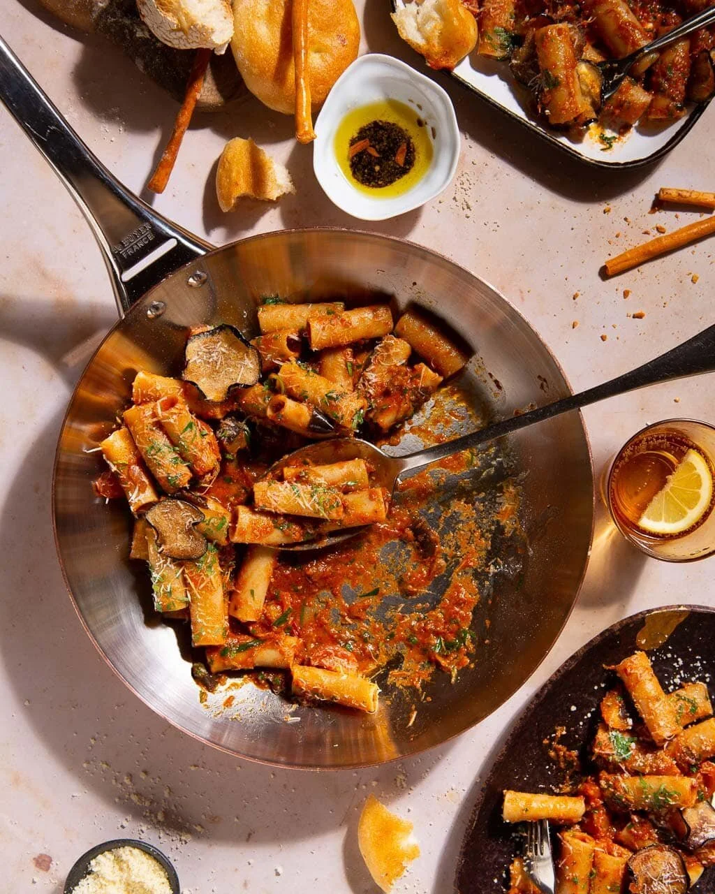 Overhead pasta spread with serving pans and small side dishes.